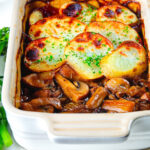 Individual vegan mushroom hotpot topped with potatoes (Lancashire) style showing the filling.