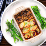 Overhead individual vegan mushroom hotpot topped with potatoes (Lancashire) style (showing filling).