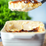 Oven baked British rice pudding being served from its baking dish.