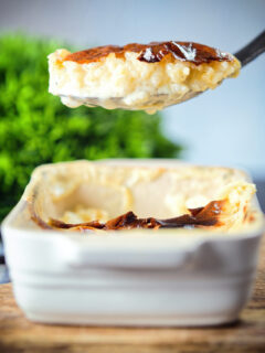 Oven baked British rice pudding being served from its baking dish.