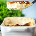 Oven baked British rice pudding being served from its baking dish.