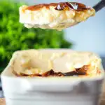 Oven baked British rice pudding being served from its baking dish.