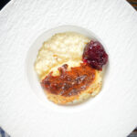 Overhead oven baked British rice pudding served with a dollop of jam.