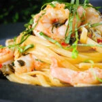 Close-up garlic chilli prawn (shrimp) linguine with fried capers and basil.