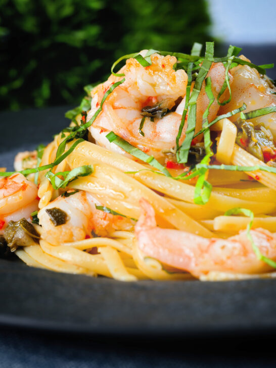 Close-up garlic chilli prawn (shrimp) linguine with fried capers and basil.