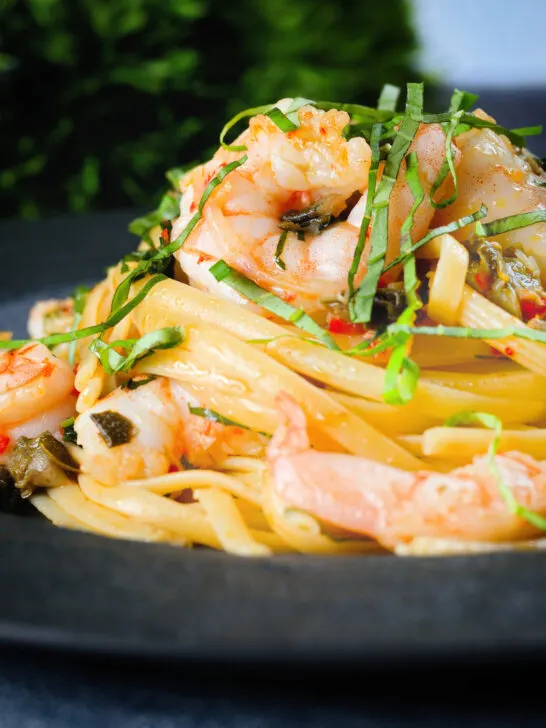 Close-up garlic chilli prawn (shrimp) linguine with fried capers and basil.