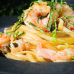 Close-up garlic chilli prawn (shrimp) linguine with fried capers and basil.