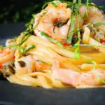 Close-up garlic chilli prawn (shrimp) linguine with fried capers and basil.