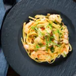 Overhead garlic chilli prawn (shrimp) linguine with fried capers and basil.