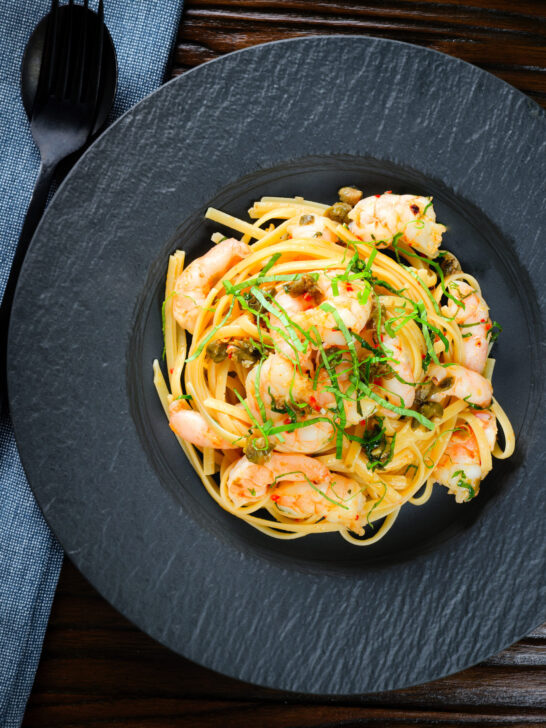 Overhead garlic chilli prawn (shrimp) linguine with fried capers and basil.