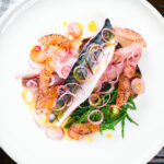Overhead salt cured mackerel fillet salad with grapefruit, samphire and toasted rye bread.