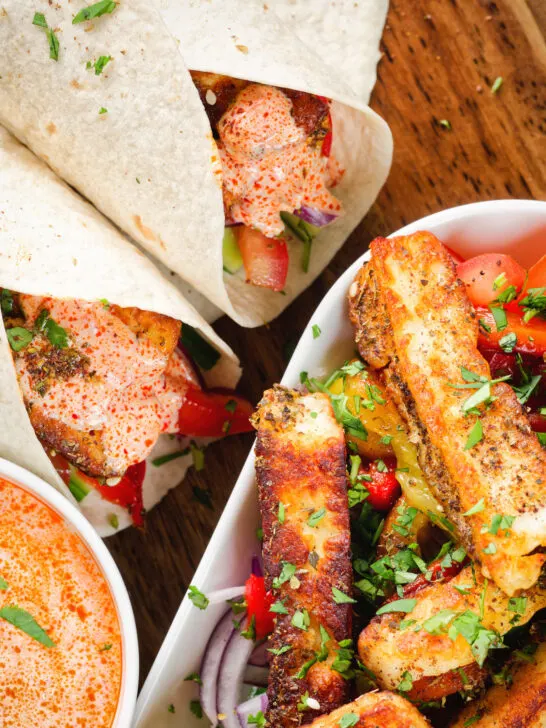Overhead close-up of crispy halloumi cheese wraps with a harissa and yoghurt sauce.