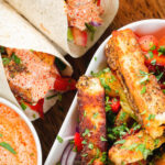 Overhead close-up of crispy halloumi cheese wraps with a harissa and yoghurt sauce.