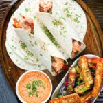 Overhead crispy halloumi cheese wraps with a harissa and yoghurt sauce.