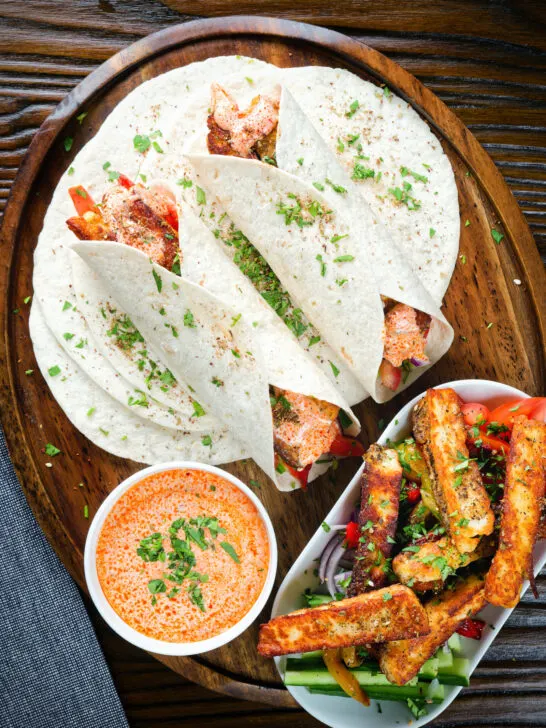Overhead crispy halloumi cheese wraps with a harissa and yoghurt sauce.