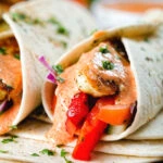 Close-up halloumi cheese and salad wraps with a harissa and yoghurt sauce.