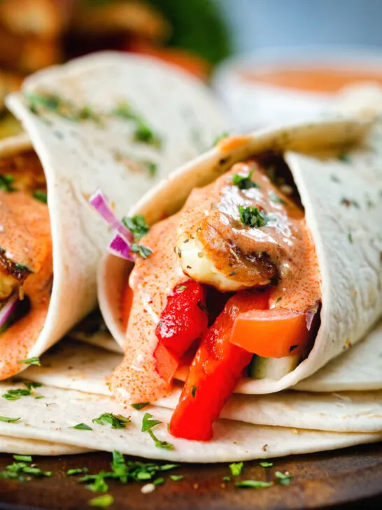 Close-up halloumi cheese and salad wraps with a harissa and yoghurt sauce.