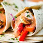 Close-up halloumi cheese and salad wraps with a harissa and yoghurt sauce.