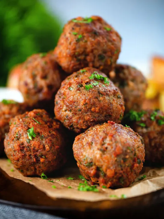 Close up fried Greek meatballs or keftedes garnished with parsley.