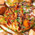 Close-up maple syrup and Worcestershire sauce glazed chicken breast with fried potatoes and braised chicory.