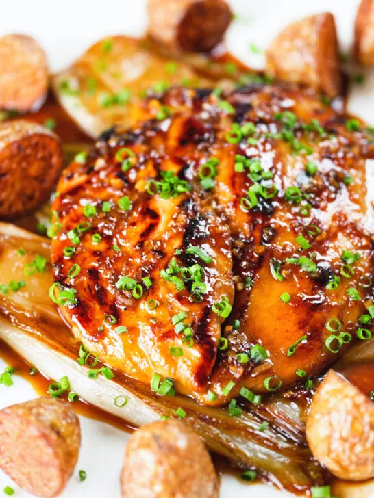 Close-up maple syrup and Worcestershire sauce glazed chicken breast with fried potatoes and braised chicory.