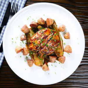 Maple syrup glazed chicken breast with fried potatoes and braised chicory.