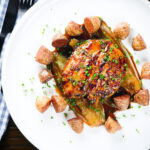 Overhead maple syrup and Worcestershire sauce glazed chicken breast with fried potatoes and braised chicory.