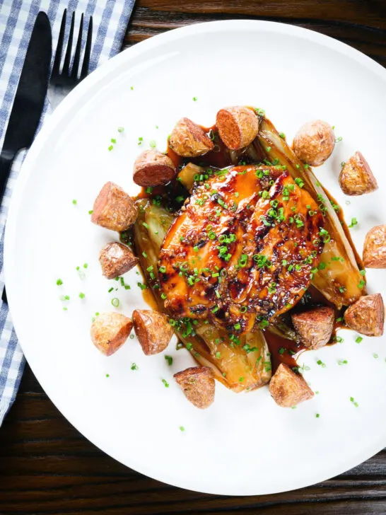 Overhead maple syrup and Worcestershire sauce glazed chicken breast with fried potatoes and braised chicory.