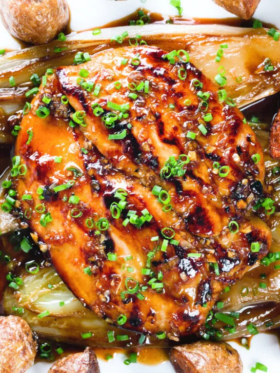 Close-up overhead maple syrup and Worcestershire sauce glazed chicken breast with fried potatoes and braised chicory.