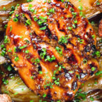 Close-up overhead maple syrup and Worcestershire sauce glazed chicken breast with fried potatoes and braised chicory.