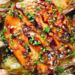 Close-up overhead maple syrup and Worcestershire sauce glazed chicken breast with fried potatoes and braised chicory.
