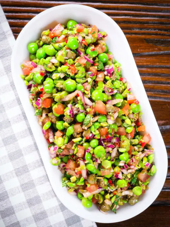 Overhead minted pea salsa or salad with capers, tomatoes chilli and red onion.