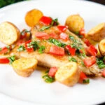 Pan fried brill fish served with sauce vierge and fried potatoes.