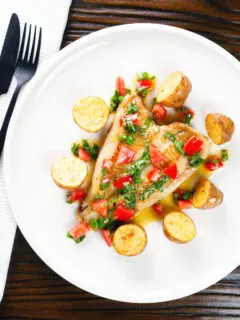 Overhead pan fried brill fish served with sauce vierge and fried potatoes.