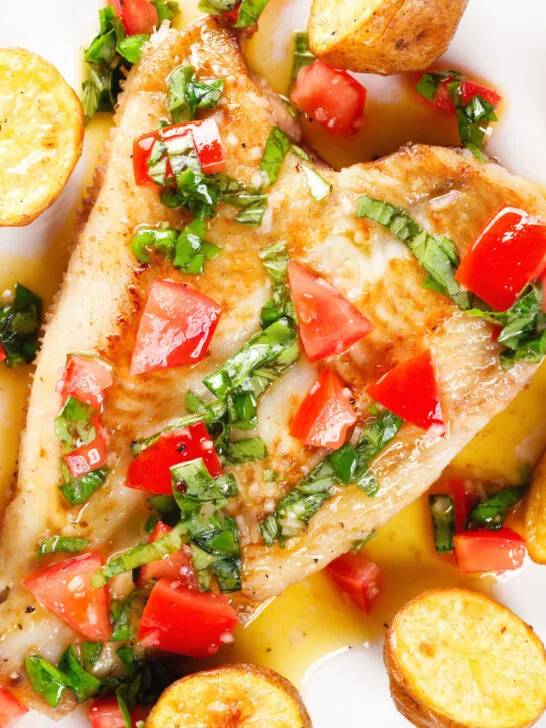 Close-up overhead pan fried brill fish served with sauce vierge and fried potatoes.