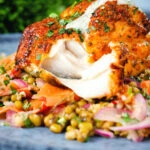 Tandoori cod cut open to show the flesh of the fish, served with a mung bean salad.