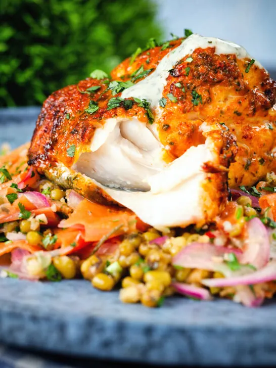 Tandoori cod cut open to show the flesh of the fish, served with a mung bean salad.