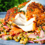 Tandoori cod cut open to show the flesh of the fish, served with a mung bean salad.