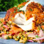 Tandoori cod cut open to show the flesh of the fish, served with a mung bean salad.