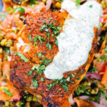 Overhead close-up tandoori cod fish with raita and a mung bean salad.