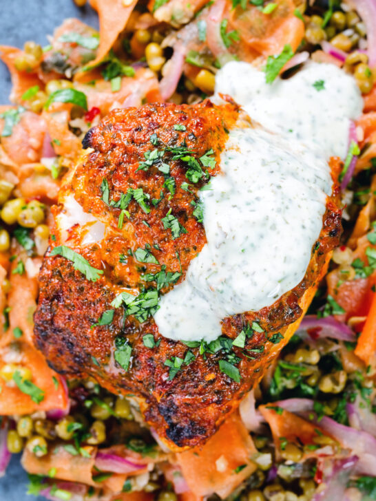 Overhead close-up tandoori cod fish with raita and a mung bean salad.