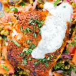 Overhead close-up tandoori cod fish with raita and a mung bean salad.