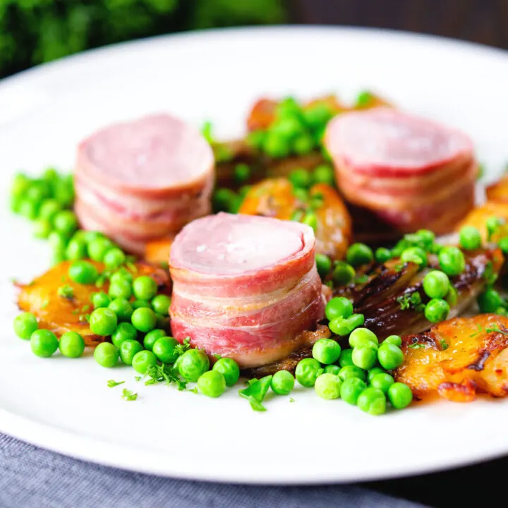 Bacon wrapped pork tenderloin, crushed roasted potatoes, braised chicory and peas.