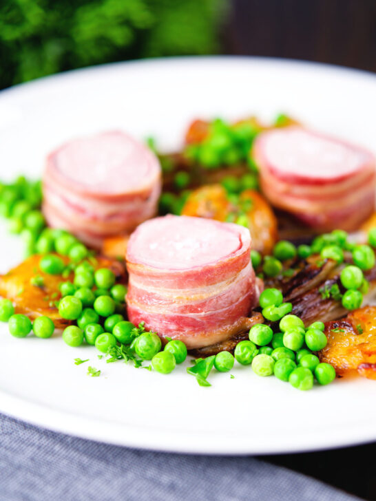 Oven Baked bacon wrapped pork tenderloin, crushed roasted potatoes, braised chicory and peas.