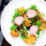Overhead bacon wrapped pork tenderloin, crushed roasted potatoes, braised chicory and peas.