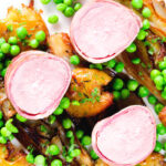 Overhead close-up bacon wrapped pork tenderloin, crushed roasted potatoes, braised chicory and peas.