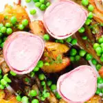 Overhead close-up bacon wrapped pork tenderloin, crushed roasted potatoes, braised chicory and peas.