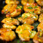 Crispy roasted crushed (smashed) new potatoes garnished with parsley.