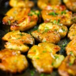 Crispy roasted crushed (smashed) new potatoes garnished with parsley.