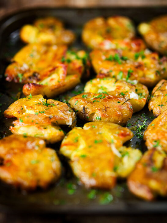 Crispy roasted crushed (smashed) new potatoes garnished with parsley.
